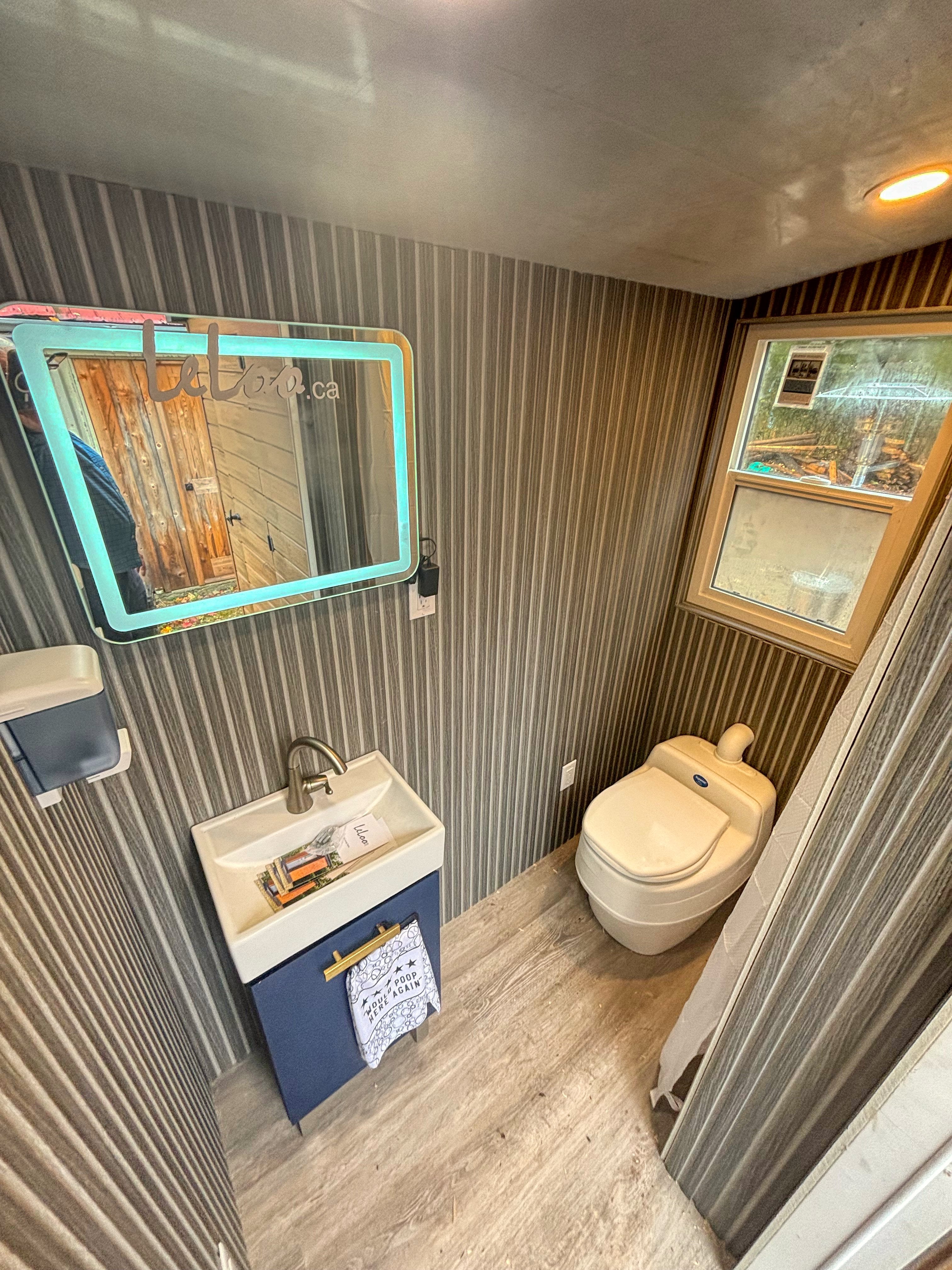 interior bathroom products of a tiny home, including a toilet, sink, and mirror